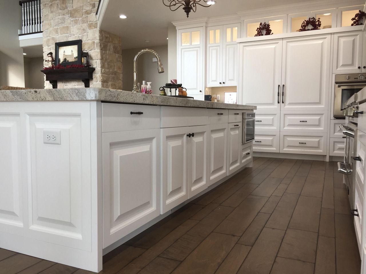 White kitchen with island, cabinets, and appliances on wood floor.