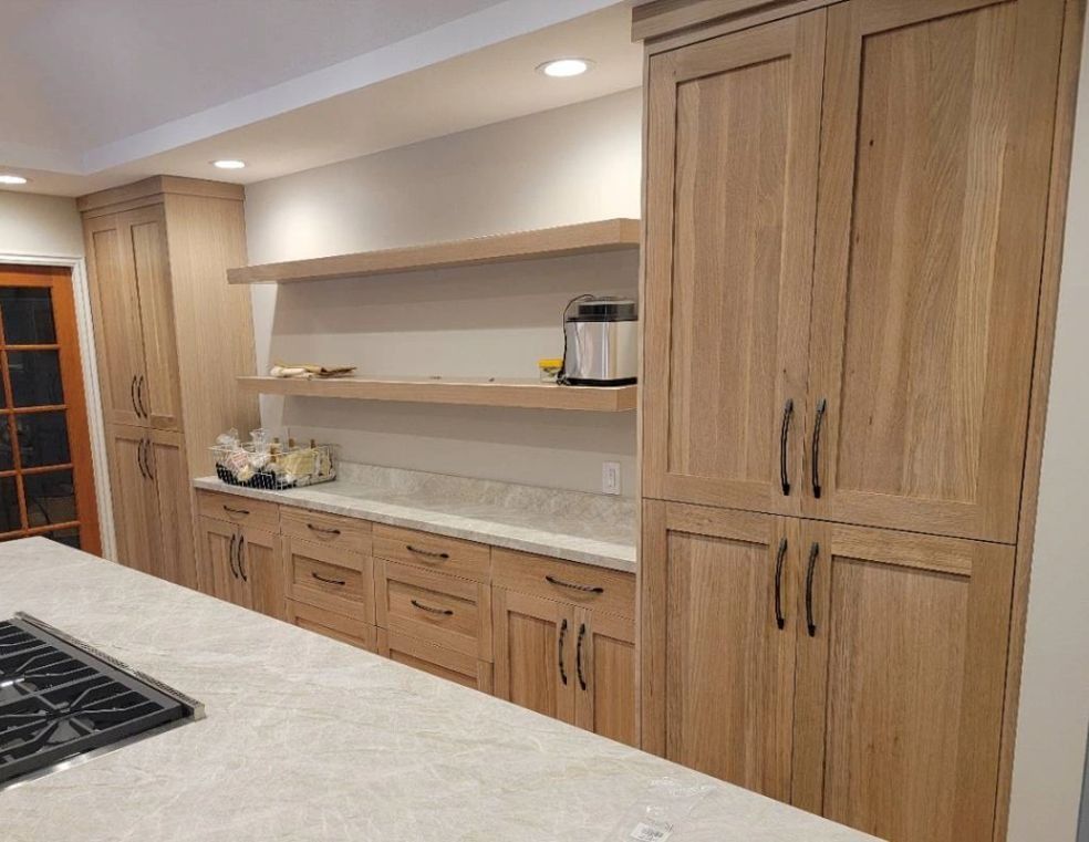 Kitchen with light wood cabinets, open shelves, and a white countertop island with a stovetop.