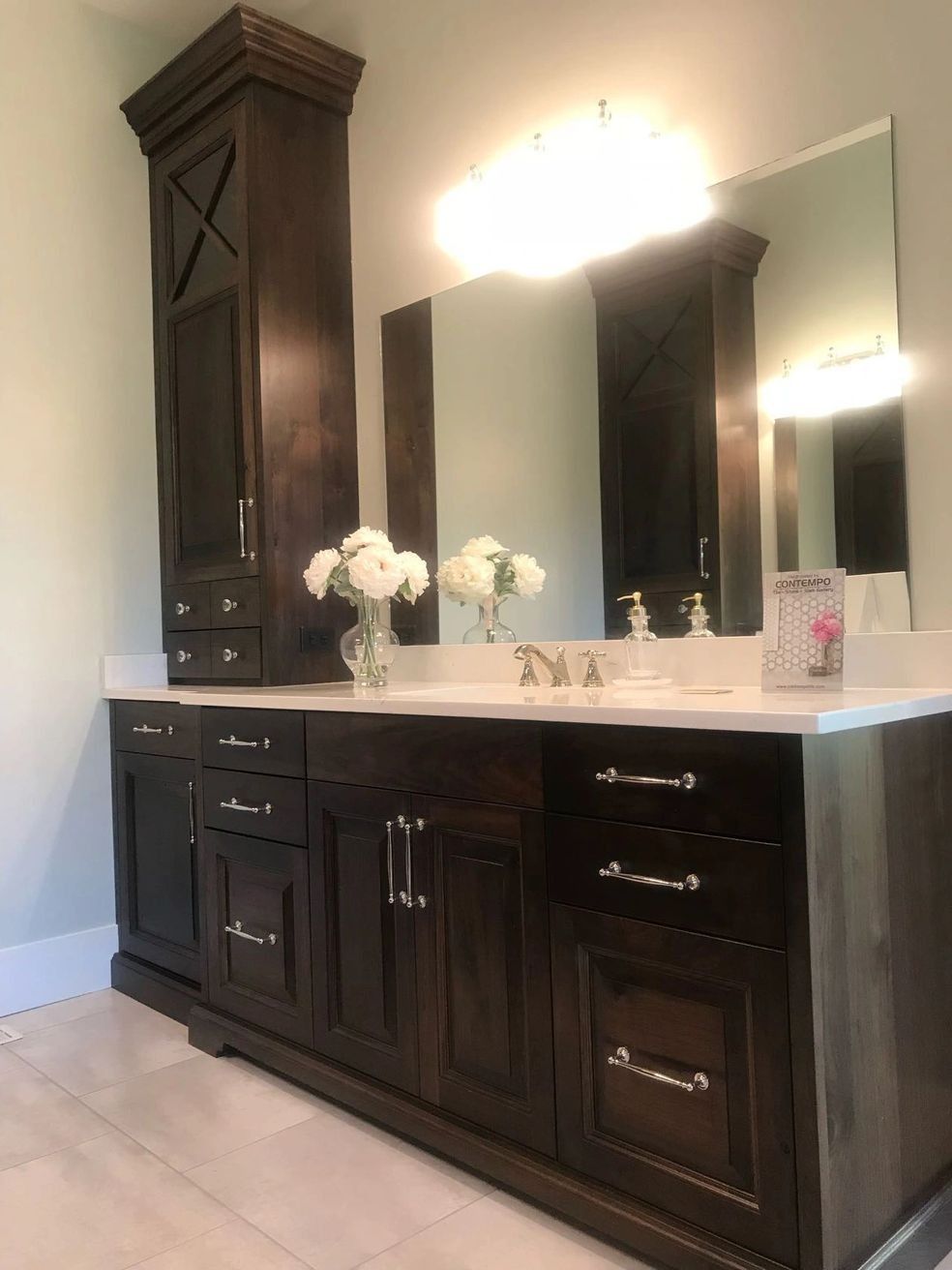 Dark wood bathroom vanity with tall cabinet, mirror, and white countertop.