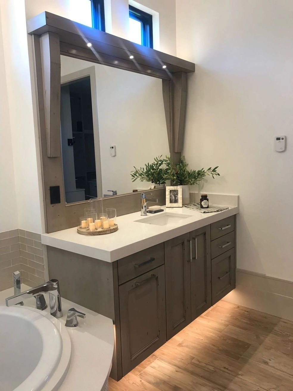 Bathroom with a vanity, large mirror, countertop, and built-in cabinets; neutral color scheme.