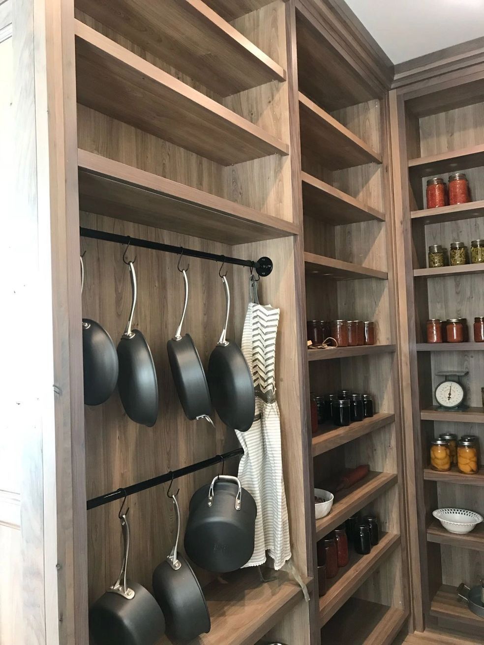 Pantry with built-in wooden shelves, a rack for pots, and canned goods.