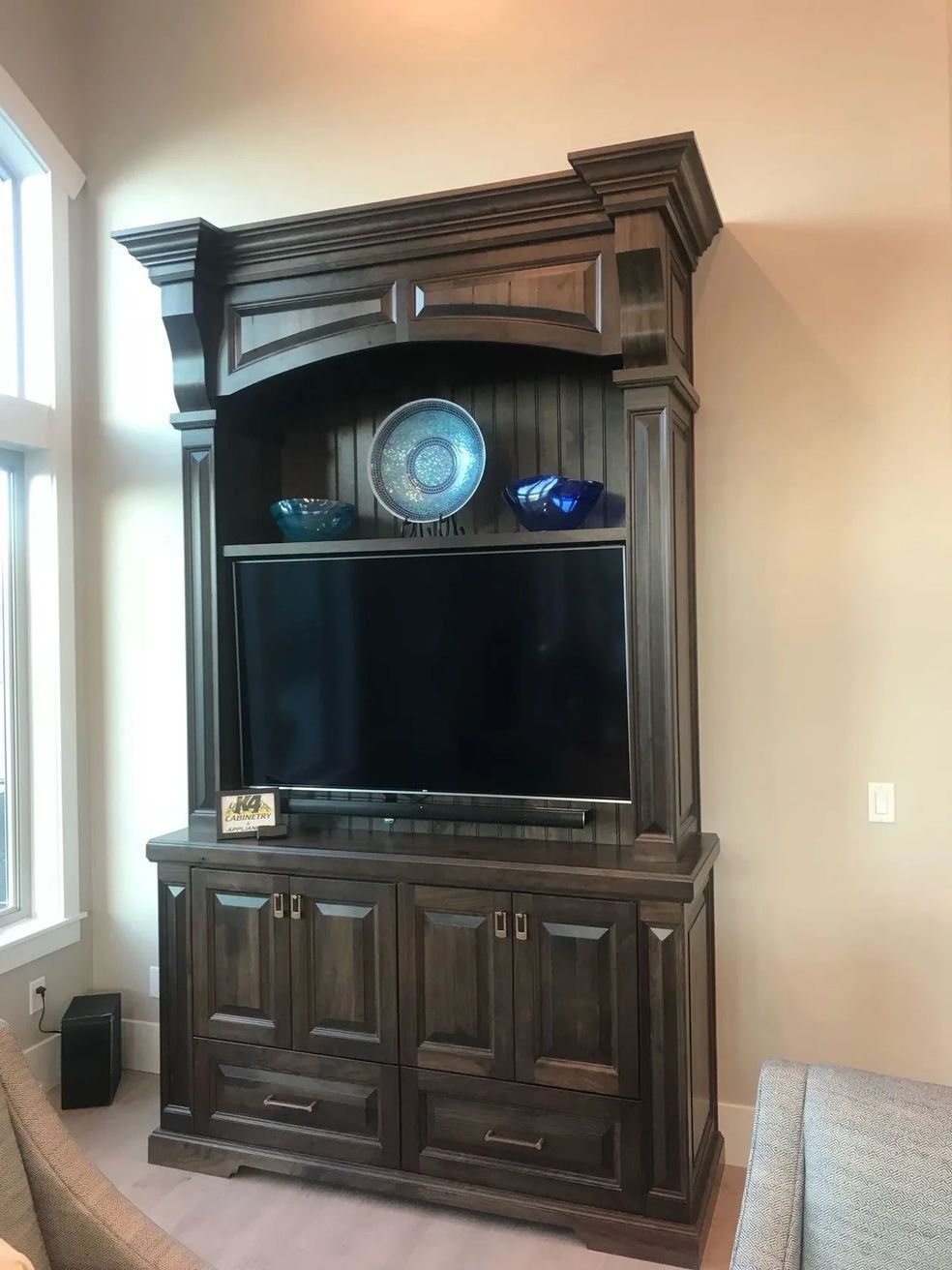 Dark wood entertainment center with TV, blue bowls, and closed cabinet doors.