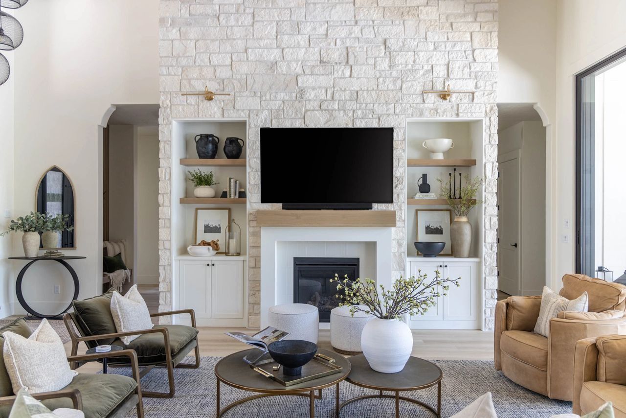 Living room with a white stone fireplace, built-in shelves, and two coffee tables surrounded by seating.