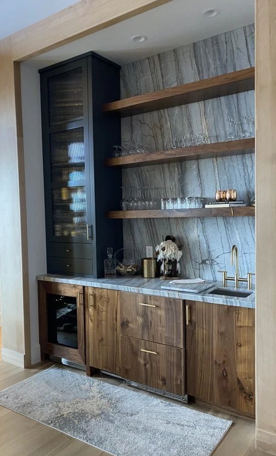 Built-in home bar with dark wood cabinets, shelves, a wine fridge, and a stone backsplash.