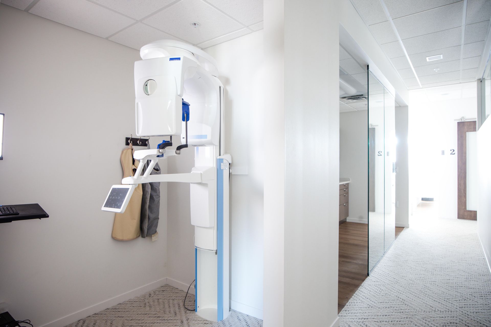Dental X-ray machine in a white room; hallway to the right