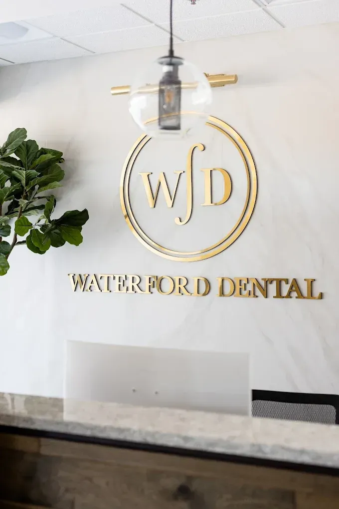 Waterford Dental reception area with gold logo, overhead light, and marble wall.