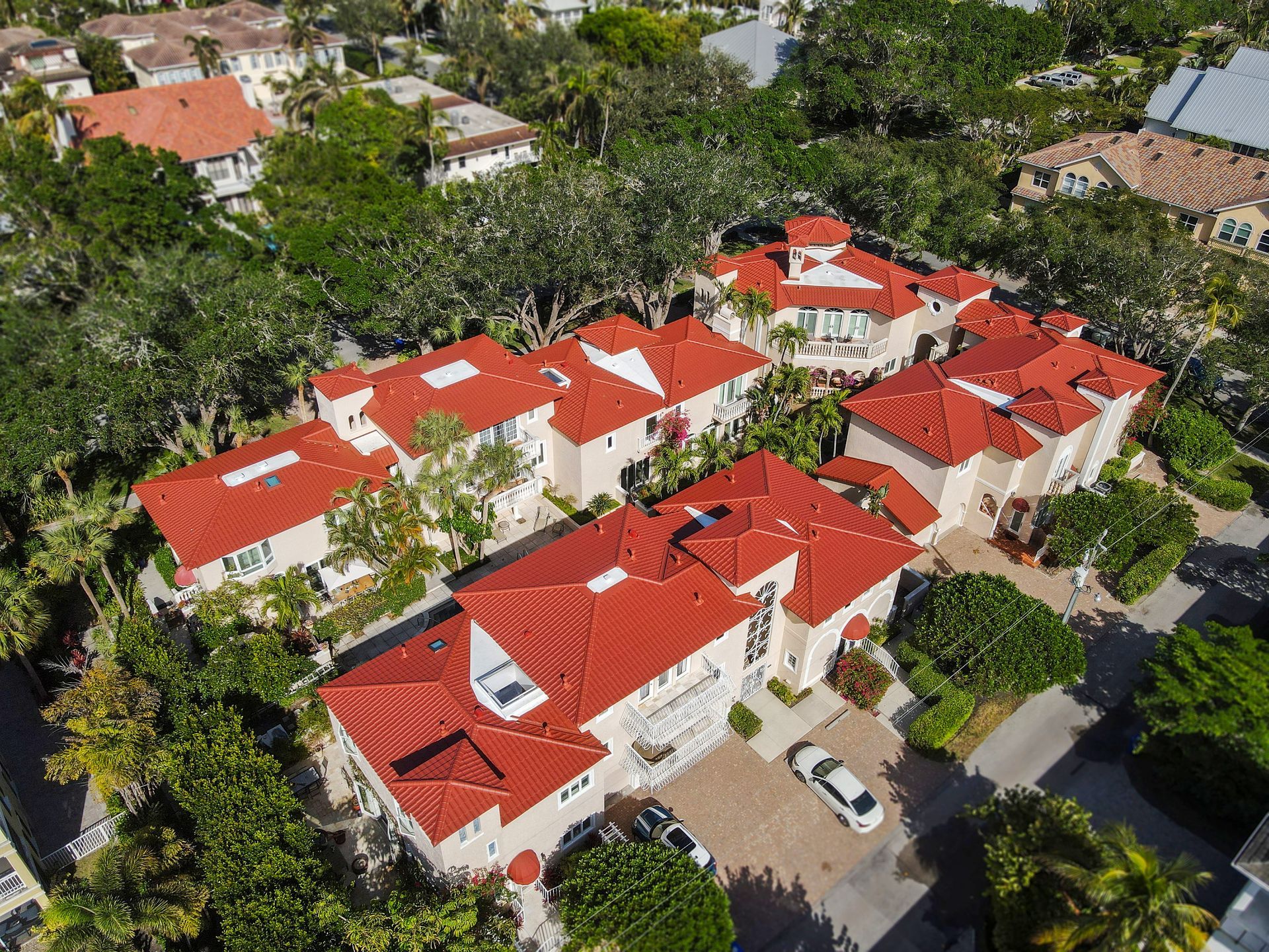 Aerial view of several homes with red tile roofs and lush green landscaping.