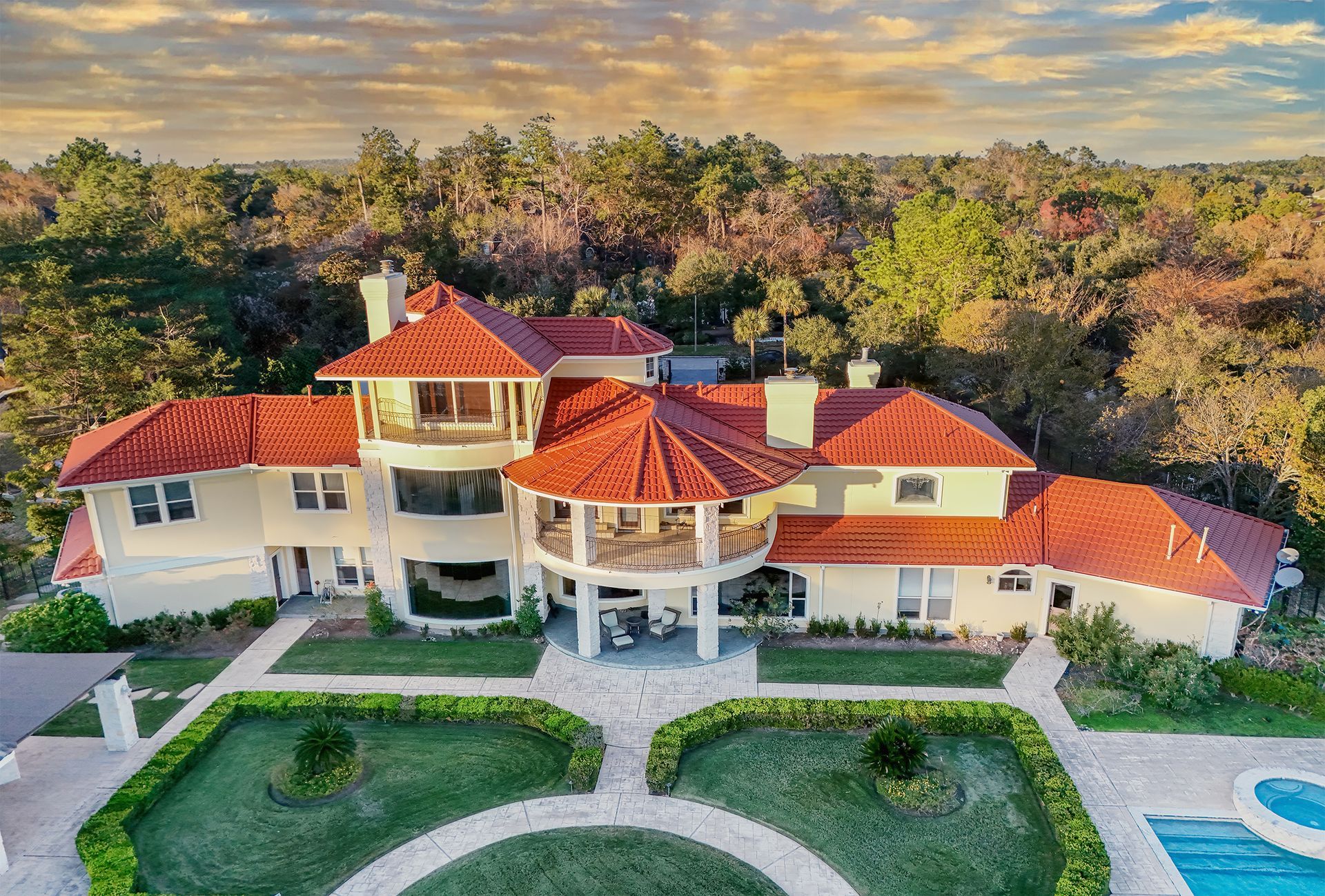 Luxury mansion with a red tile roof and manicured grounds.