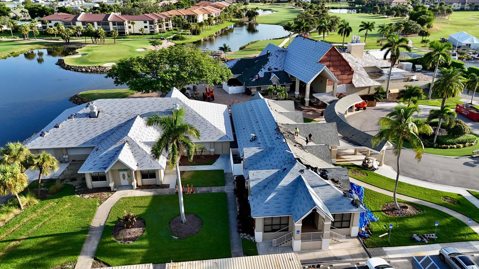 Aerial view of a residential complex with buildings, green lawns, a lake, and a golf course.
