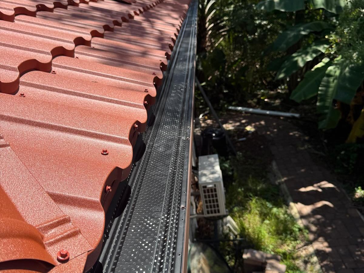 Red tiled roof with black gutter guard.
