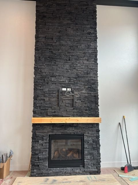 A black brick fireplace with a wooden mantle in a living room.