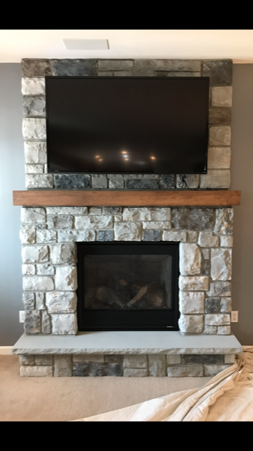 A stone fireplace with a flat screen tv above it.