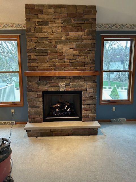 A living room with a brick fireplace and two windows.