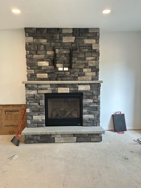 A stone fireplace in a living room with a broom on the floor