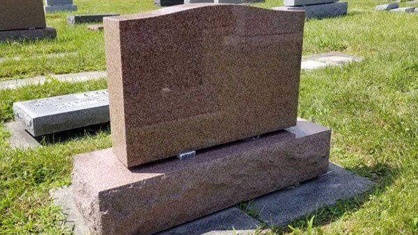A gravestone is sitting in the grass in a cemetery.