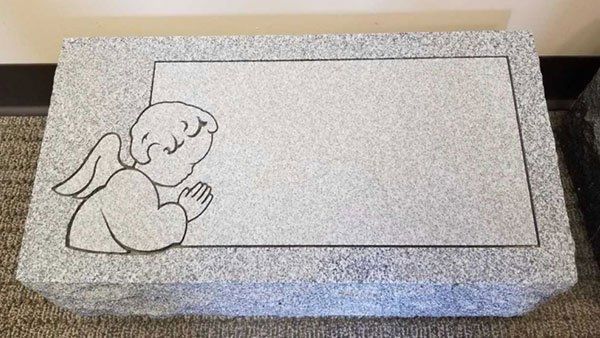 A gravestone with a drawing of an angel on it.