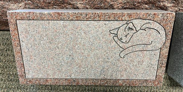 A gravestone with a drawing of a cat on it.