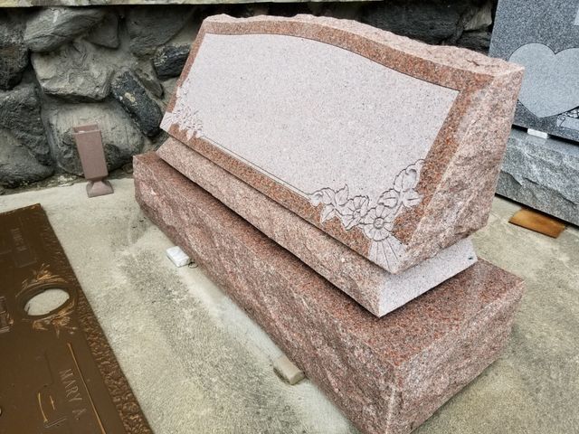 A black and white gravestone with a painting of a farm at night.