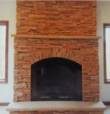 A living room with a brick fireplace and two windows.