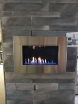 A fireplace is built into a stone wall in a living room.