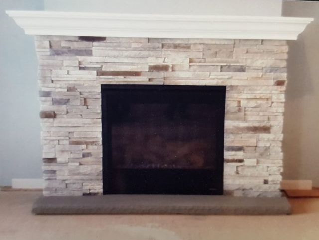 A stone fireplace with a black screen and a white mantle