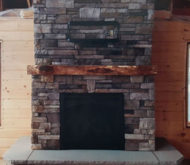 A large stone fireplace with a wooden mantle