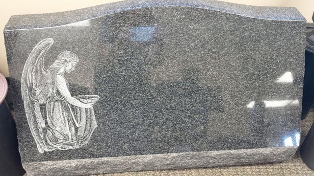 A gravestone with a picture of an angel on it.