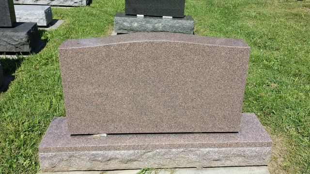 A gravestone is sitting on top of a grave in a cemetery.