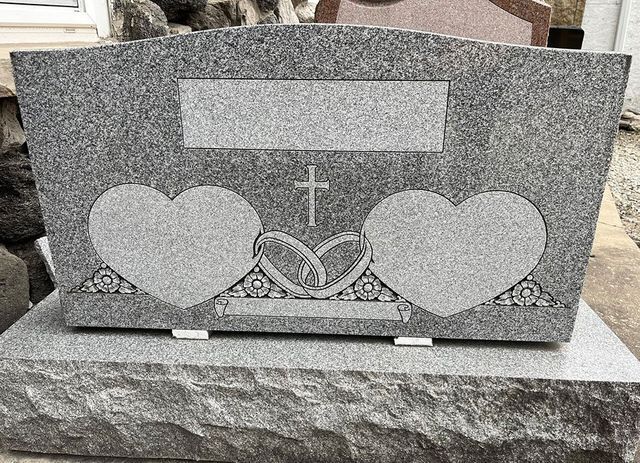 A gravestone with two hearts and a cross on it.