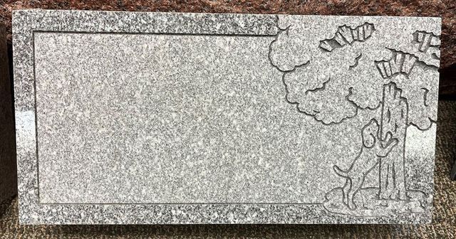 A gravestone with a drawing of a person on it is sitting on a carpet.