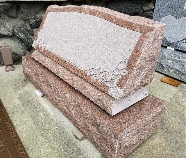 A gravestone is sitting on top of another gravestone on the ground.