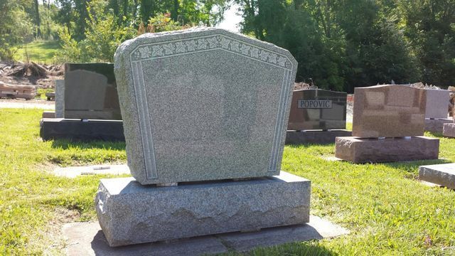 A gravestone in a cemetery with a lot of graves in the background.