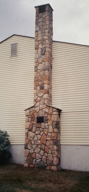A large stone chimney on the side of a house