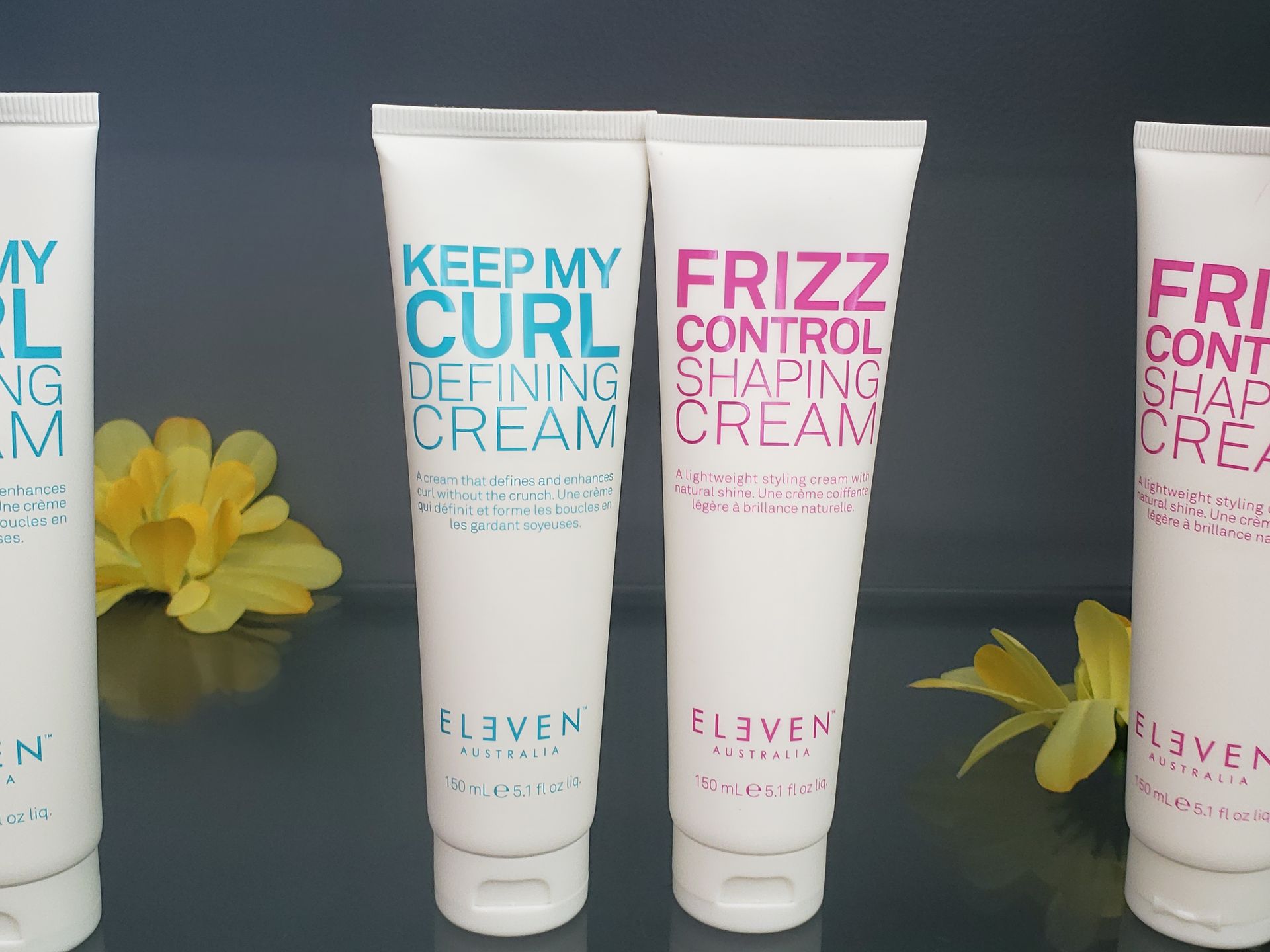 Four tubes of frizz control shaping cream are lined up next to each other