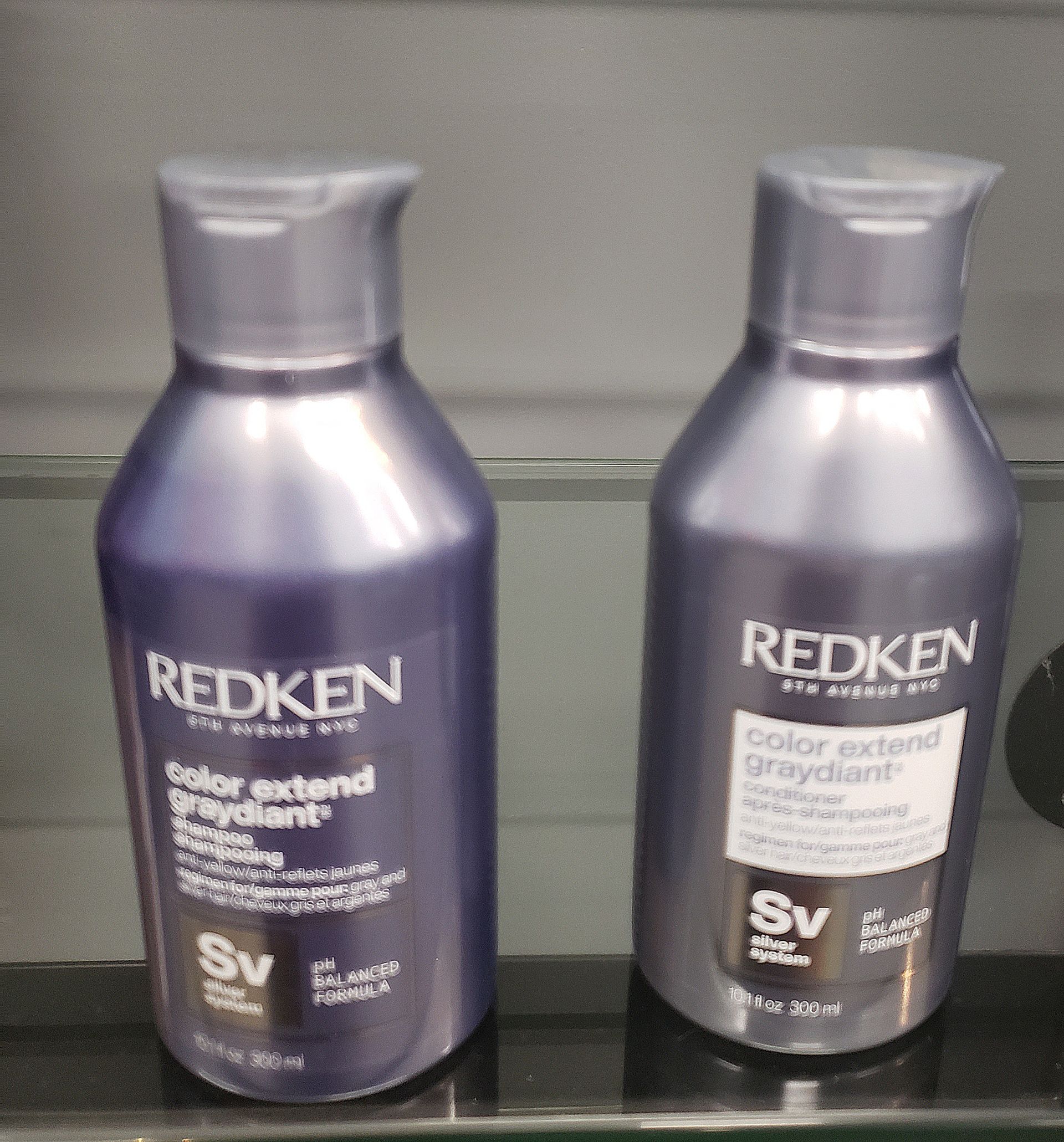 Two bottles of redken shampoo and conditioner on a shelf