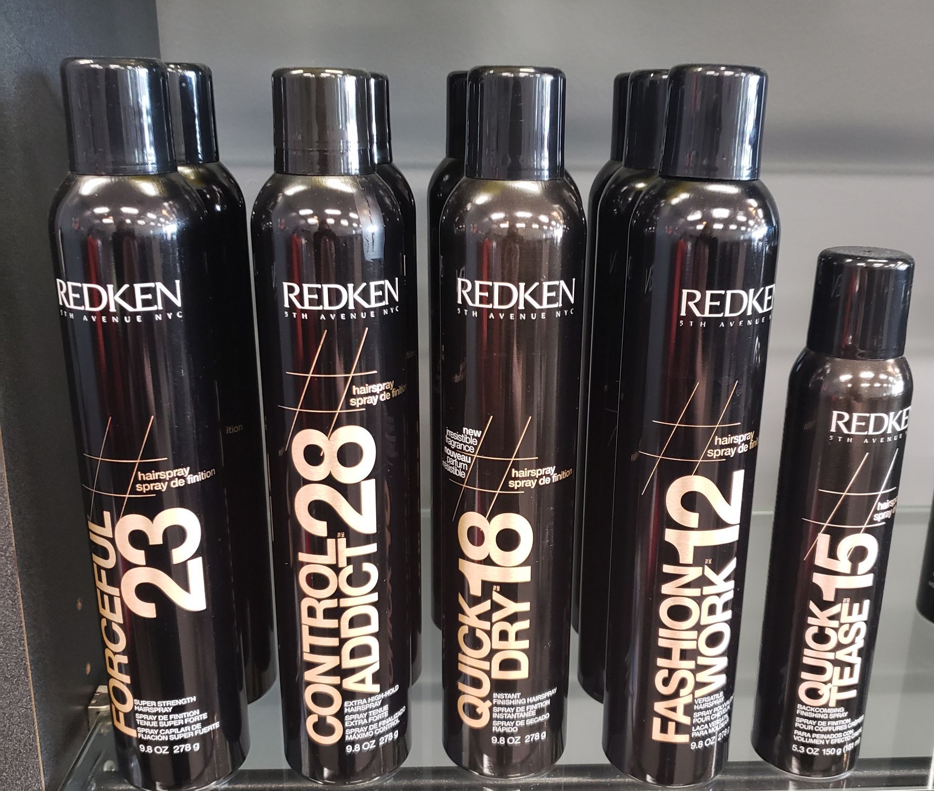 Several bottles of redken hair products are lined up on a shelf
