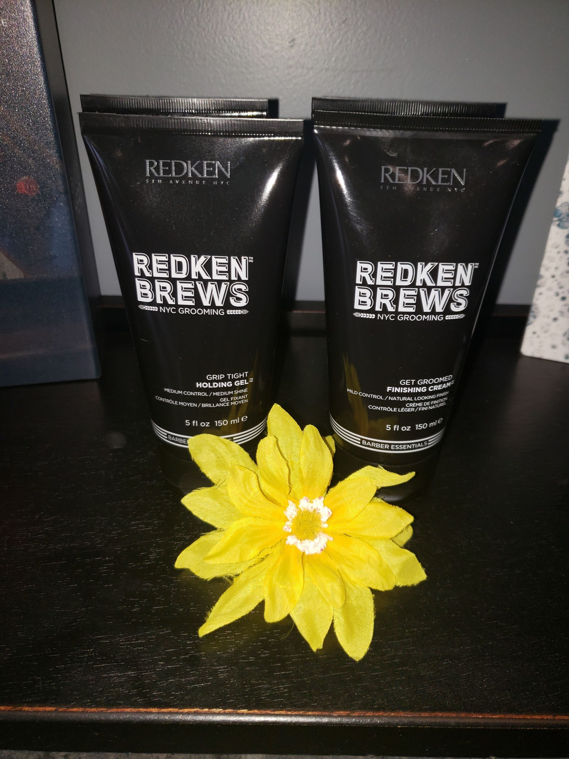 Two bottles of redken brews next to a yellow flower