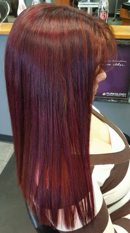 A woman with long red hair is sitting in a chair in a salon.