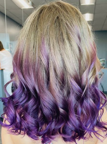 A woman with blonde and purple hair is standing in a room.