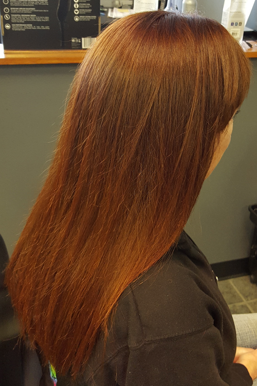A woman with long brown hair is sitting in a chair.