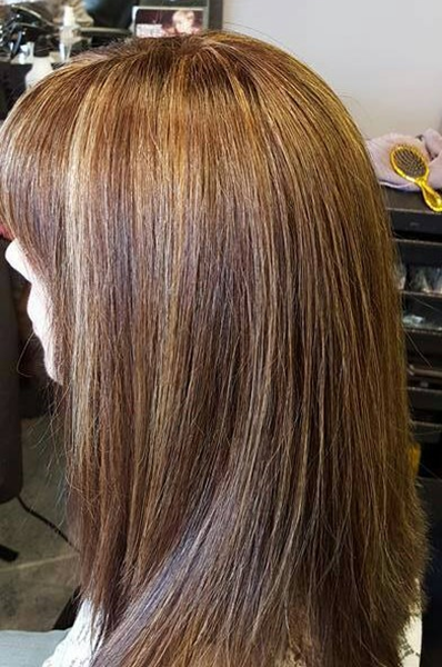 A woman is getting her hair cut in a salon.