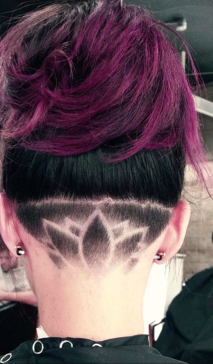 A woman with purple hair has a shaved design on the back of her head.