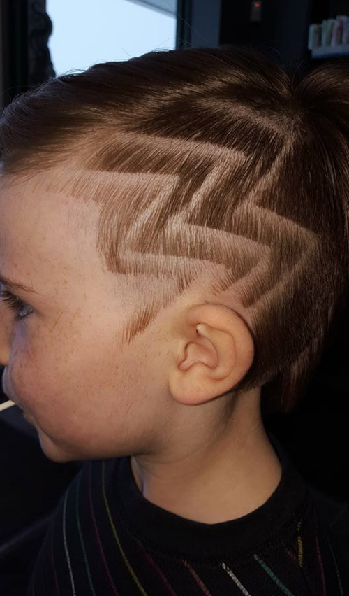 A young boy with a shaved design in his hair.