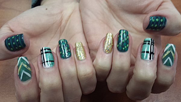 A close up of a person 's nails with green and gold designs