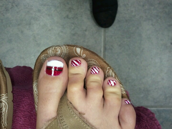 A close up of a person 's feet with red and white nail polish