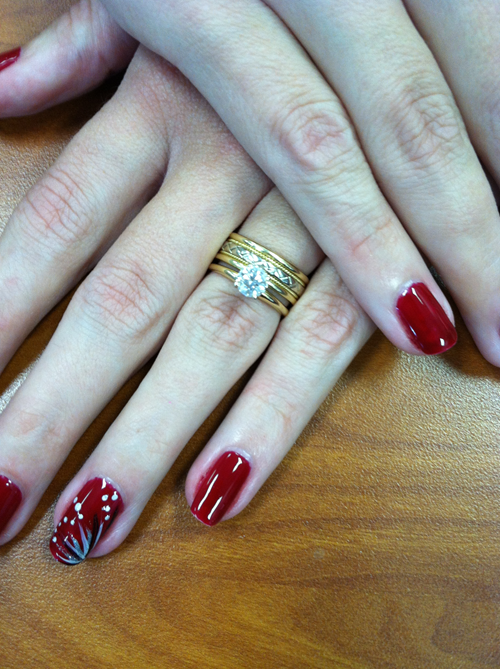 A woman 's hands with red nails and a gold ring