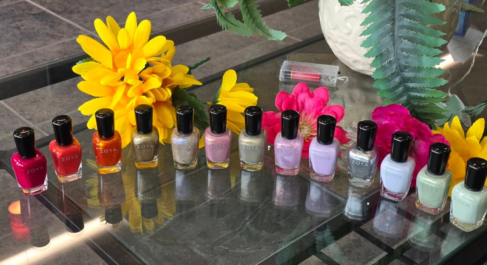 A table topped with bottles of nail polish and flowers.
