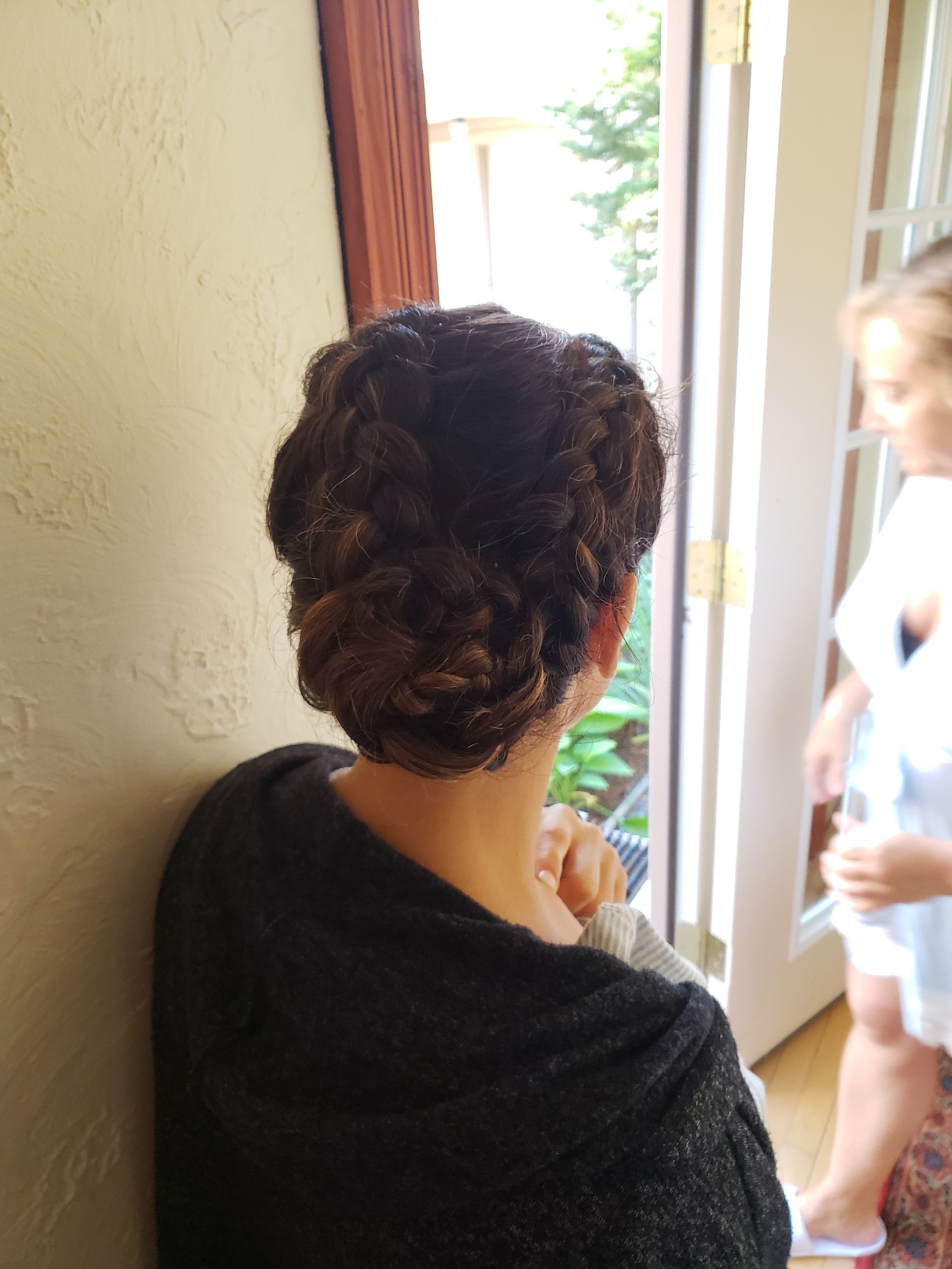 A woman with her hair in a bun is standing in front of a door