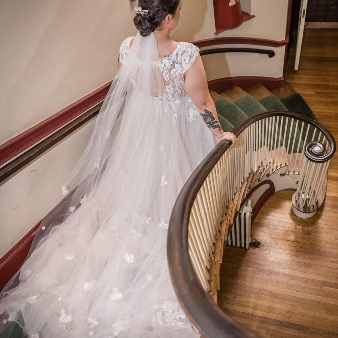 A bride in a wedding dress is standing on a set of stairs.