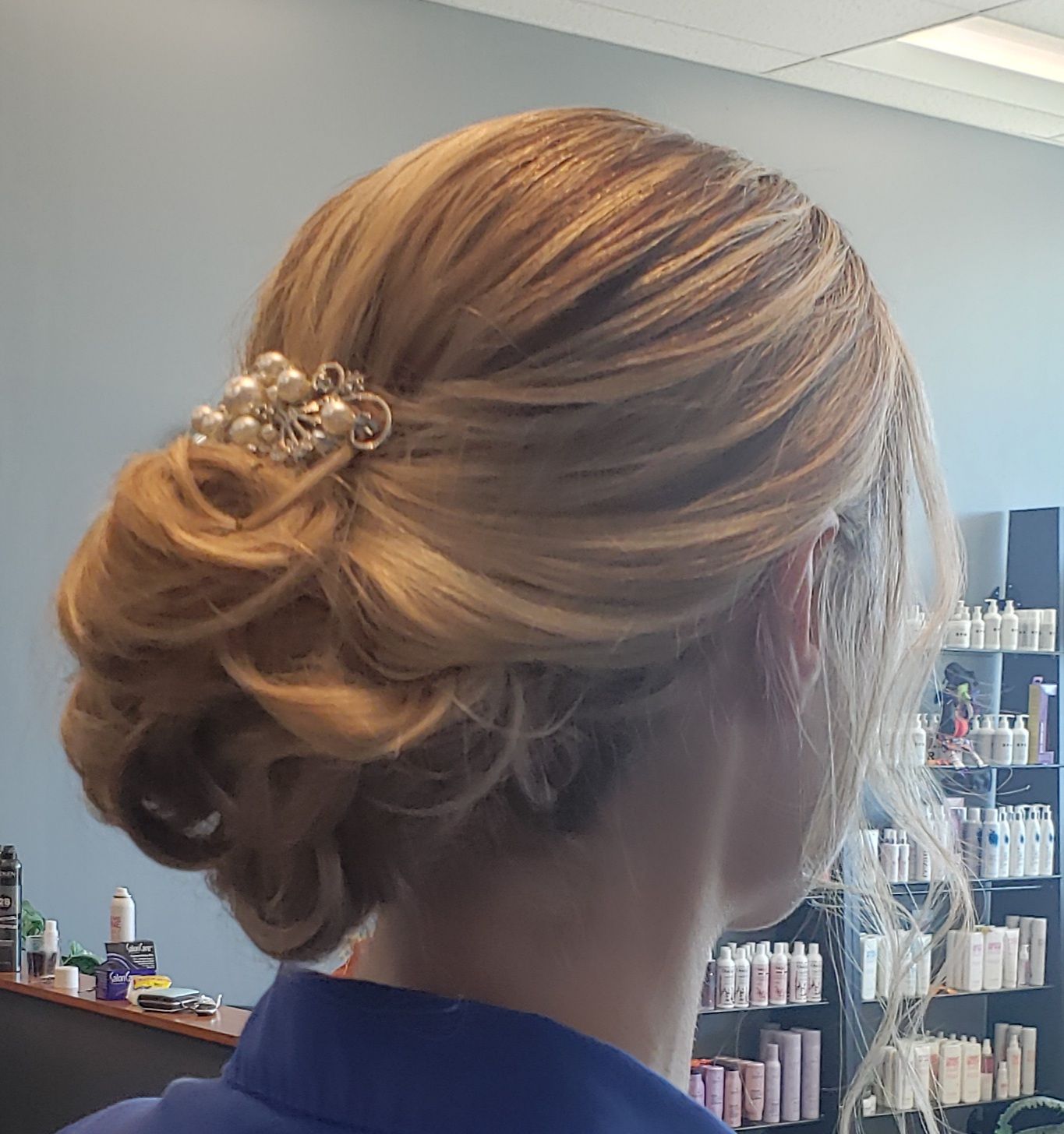 A woman is wearing her hair in a bun with pearls in it